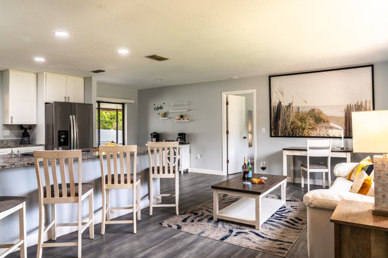 A modern kitchen with a built-in refrigerator, wooden chairs, a dining table, and a coffee station.
