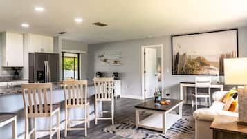 A modern kitchen with a built-in refrigerator, wooden chairs, a dining table, and a coffee station.