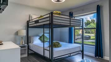 A bunk bed room with a desk, lamp, and a view of the outside.