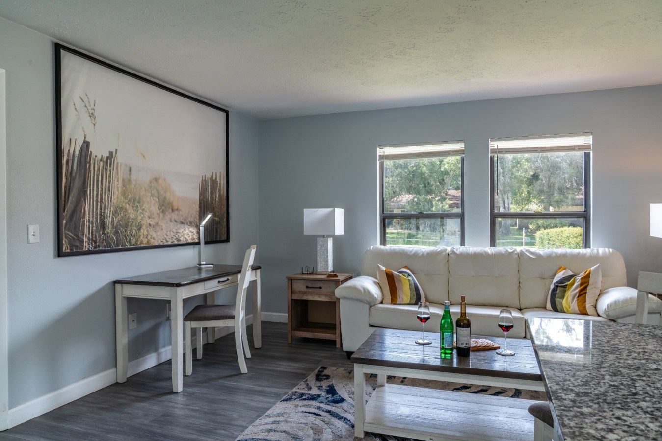 Un salon moderne avec un canapé blanc, une table à manger et un grand tableau accroché au mur.