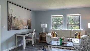 Un salon moderne avec un canapé blanc, une table à manger et un grand tableau accroché au mur.
