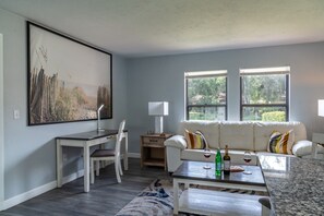 Ein modernes Wohnzimmer mit einem weißen Sofa, einem Esstisch und einem großen Gemälde an der Wand.