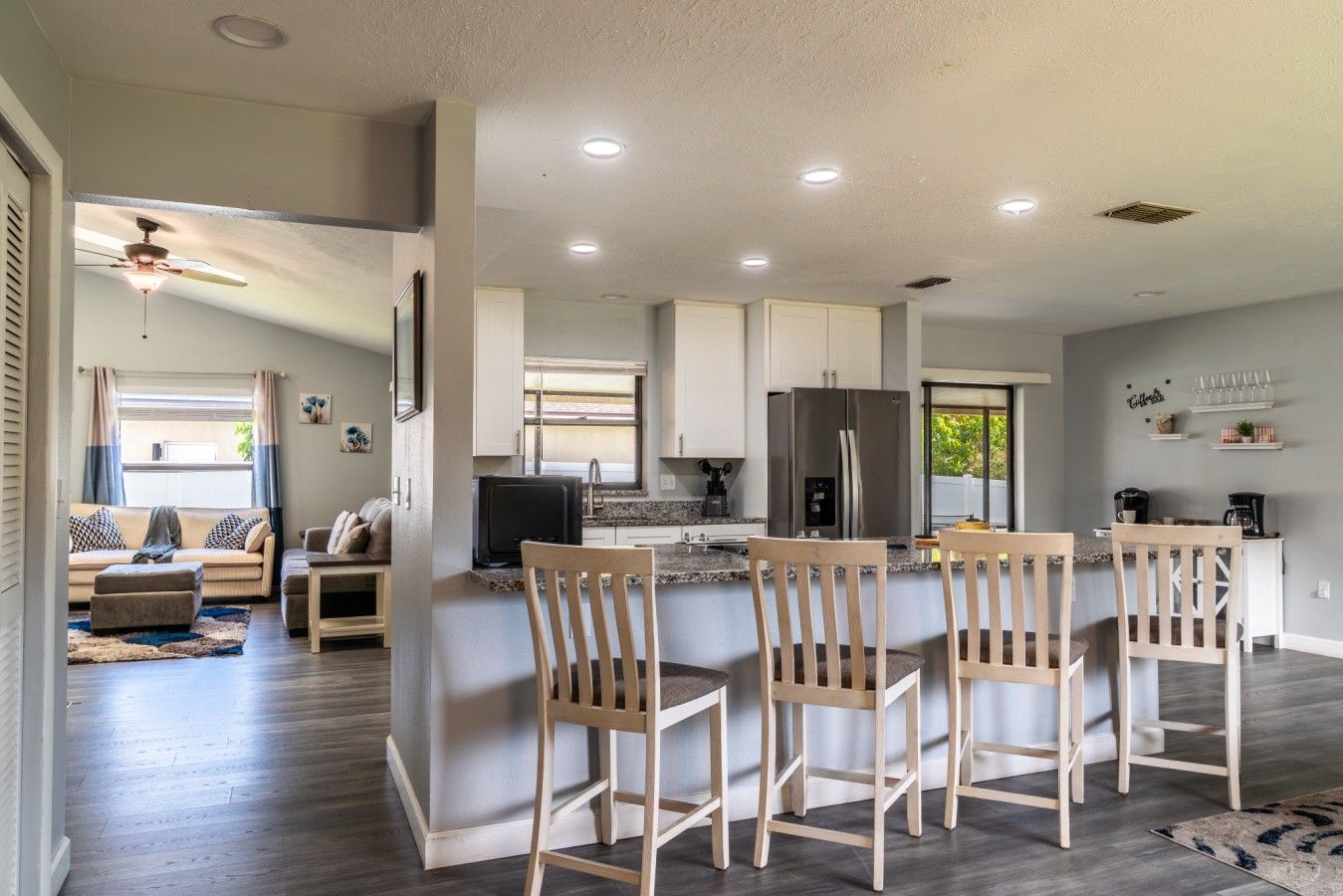 A modern kitchen with a central island, bar stools, and a dining area with a table and chairs.