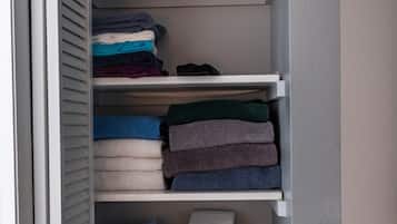 Un placard avec plusieurs étagères où sont rangées des serviettes et des couvertures pliées.