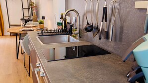 Uma cozinha moderna com pia embutida, um suporte para utensílios pendurado e um eletrodoméstico azul no balcão.