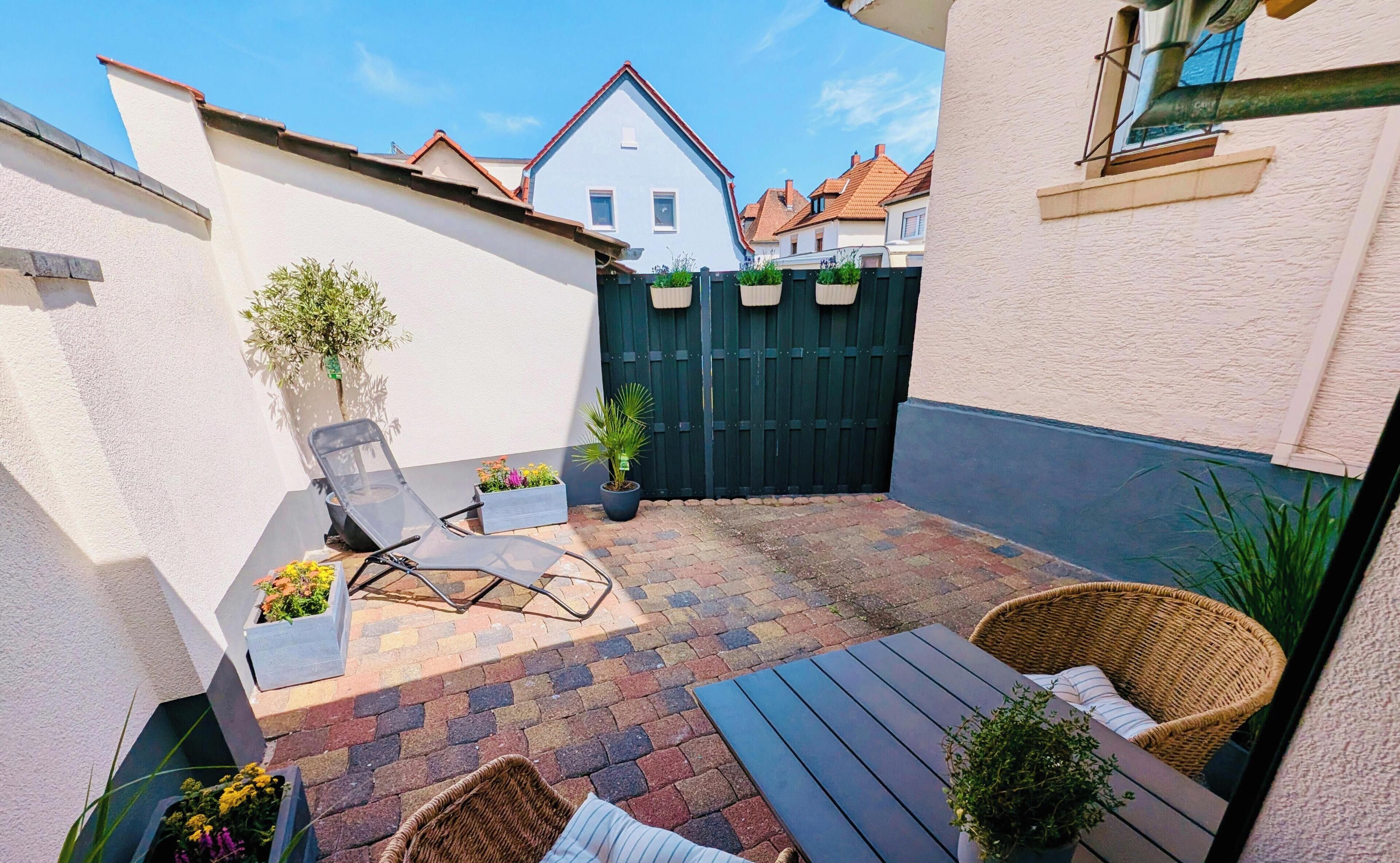A patio with a table, chairs, and potted plants.