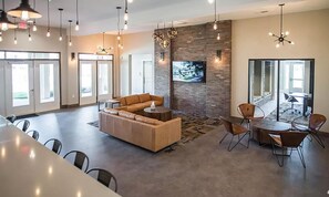 A spacious lobby with a large seating area, a brick accent wall, and a flat-screen TV mounted above it. - Landing | Amazing 2BD, Pool, Game Room (Spartanburg)