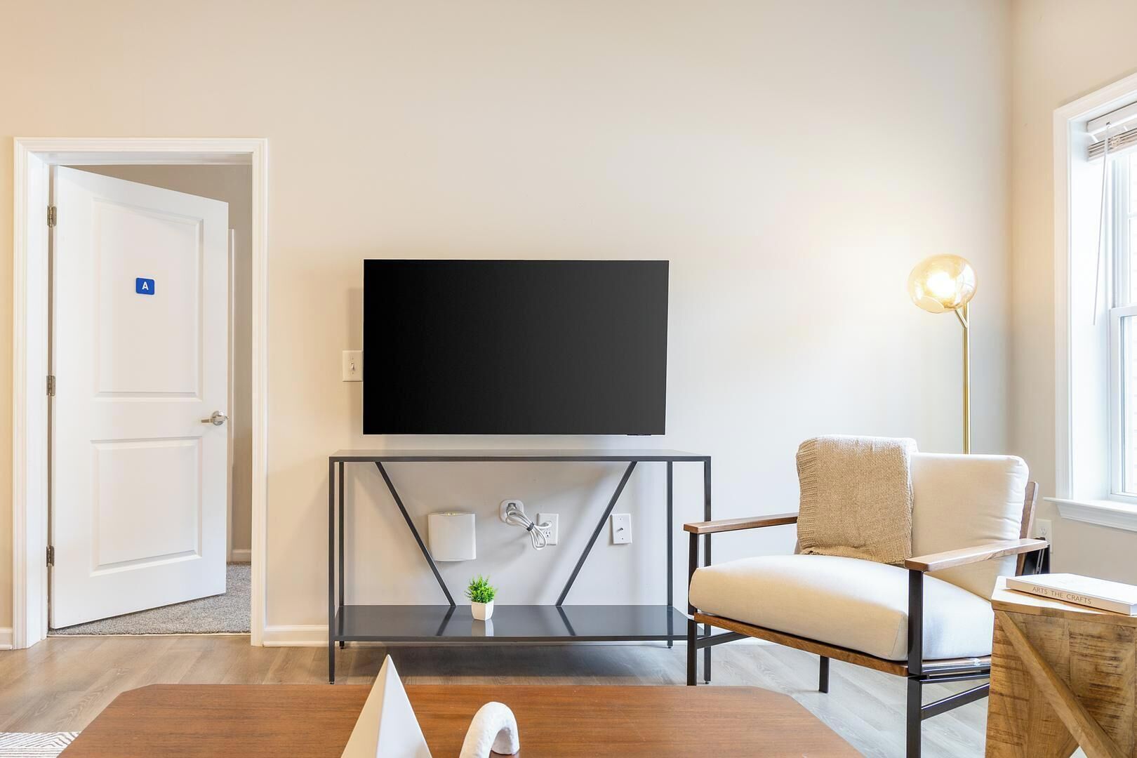 Una sala de estar moderna con una televisión de pantalla plana, un sofá, una mesa de centro y una lámpara de pie.