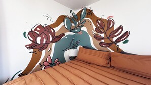 A bed with a brown cover, a white pillow, and a wall with a floral mural. - Sleeps 8 • Pet Friendly • Near Mall of America (Saint Paul)