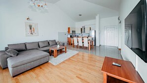 A modern living room with a grey sofa, wooden coffee table, and a TV on a stand. - Seaview apartment Verde near beach (Okrug Gornji)