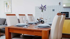 A dining table set with plates, glasses, and a bottle, surrounded by chairs. - Seaview apartment Verde near beach (Okrug Gornji)