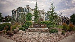 A multi-story apartment building with a sign reading 'Copperwood Apartments' and the number '5657'.
