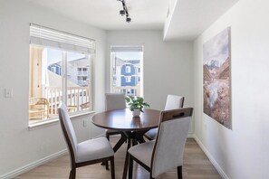 Ein Essbereich mit einem runden Tisch, vier Stühlen, einer Zimmerpflanze und einem Bild an der Wand.