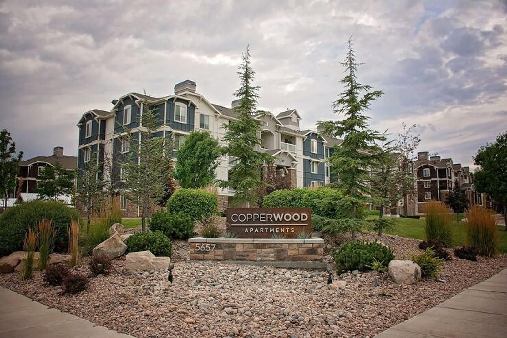 A multi-story apartment building with a sign reading 'Copperwood Apartments' and the number '5657'.