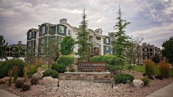 A multi-story apartment building with a sign reading 'Copperwood Apartments' and the number '5657'.