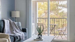 A living room with a sofa, a lamp, and a table with a book and a plant. - Landing | Incredible 1BD, Gym, Clubhouse (Richland)