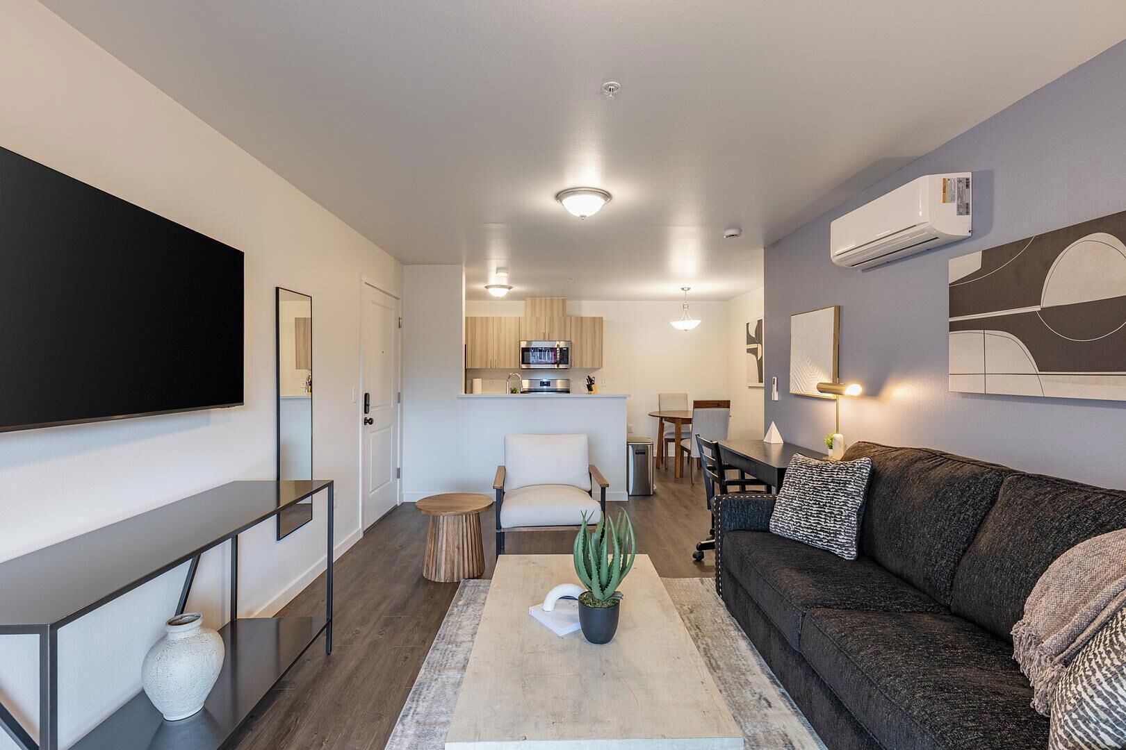 Un salon moderne avec un téléviseur à écran plat, un canapé, une table basse et un coin repas à l’arrière-plan.