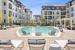 A swimming pool with lounge chairs, surrounded by multi-story buildings with balconies. - Landing | Stunning 2BD in Manhattan Harbour (Cincinnati)