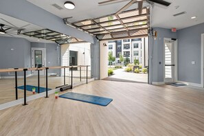 A spacious room with a large mirror, exercise equipment, and a view of the outside. - Landing | Stunning 2BD in Manhattan Harbour (Cincinnati)