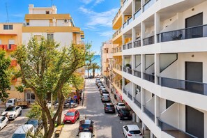 A multi-story residential building with balconies, parked cars, and a clear sky. - "Pé na Areia" by Centralgarve (Loulé)