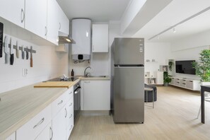 A modern kitchen with white cabinetry, a stainless steel refrigerator, and a built-in oven. - Pé na Areia by Centralgarve (Loulé)