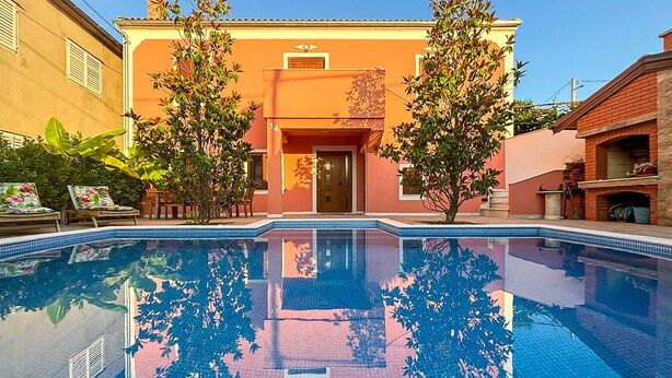 A swimming pool with a reflection of trees and a building with a door and windows.