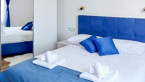 A hotel room with a large bed, two nightstands, a mirror, and a blue headboard.