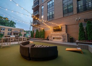 An outdoor patio with a sofa, chairs, a grill, and a fireplace. - Landing | Modern 1BD, Gym (Columbus)