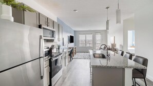 Une cuisine moderne dotée d’appareils électroménagers en acier inoxydable, d’un îlot central avec un comptoir en granit et d’un coin repas offrant une vue agréable.