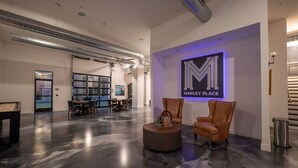 A spacious lobby with a polished floor, a reception desk, seating area, and a large wall sign. - Landing | Incredible 1BD, Gym (Columbus)