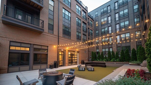 A courtyard with outdoor seating, a fire pit, and string lights. - Landing | Incredible 1BD, Gym (Columbus)