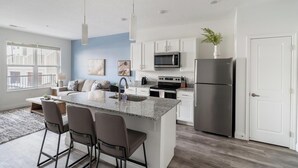 A modern kitchen with a central island, stainless steel appliances, and a view to the outside. - Landing | Incredible 1BD, Gym (Columbus)