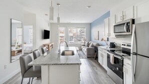 A modern kitchen with a central island, stainless steel appliances, and a view to the outside. - Landing | Incredible 1BD, Gym (Columbus)