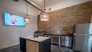 Una cocina moderna con protector mural de piedra, electrodomésticos de acero inoxidable y una isla central con un mueble de madera.