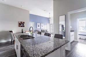 Una cocina moderna con encimeras de granito, un fregadero y un comedor con sillas.