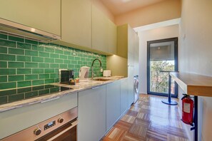 A modern kitchen with a green backsplash, stainless steel appliances, and a built-in oven. - 207 Bella Vista Porto Apartment (Porto)