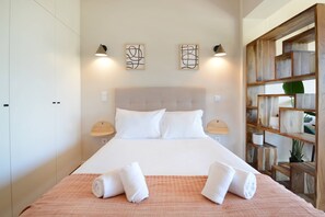 A neatly made bed with white linens, two wall-mounted lamps, and a wooden shelf unit with decorative items. - 207 Bella Vista Porto Apartment (Porto)