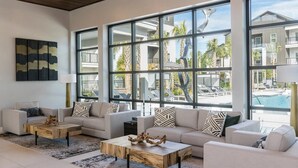 A modern living room with large windows, a pool view, and a minimalist design. - Landing | Chic 1BD, Yoga Studio, Gym (Summerville)