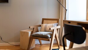 A wooden chair with a cushion, a desk, a lamp, and a television on the wall. - VIVA Santa Catarina  Serviced Apartments -2 (Porto)