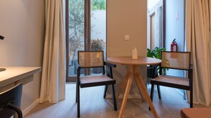 A room with a round wooden table, two wicker chairs, a small potted plant, and a fire extinguisher on the wall. - VIVA Santa Catarina Serviced Apartments -3 (Porto)