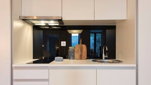 A modern kitchen with a built-in stove, a sink, and a wooden cutting board. - VIVA Santa Catarina Serviced Apartments -3 (Porto)