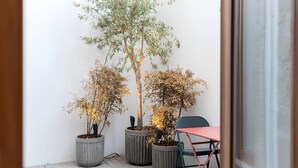 A small outdoor seating area with a table and chairs, surrounded by potted plants. - VIVA Santa Catarina Serviced Apartments -3 (Porto)