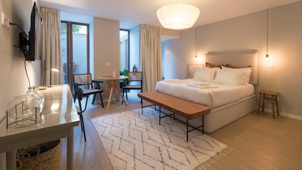 A modern hotel room with a bed, bedside table, lamp, and a view of the outdoors. - VIVA Santa Catarina Serviced Apartments -3 (Porto)