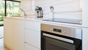 Una cocina moderna con armarios blancos, horno de acero inoxidable y salpicadero de mármol.
