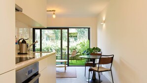 Een moderne keuken met een eetgedeelte, grote ramen en uitzicht op een tuin.