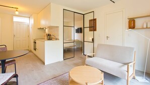 Een knus woongedeelte met een kitchenette, een bank, een eettafel en een televisie.