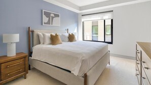 Una camera da letto con un letto, un comodino, una cassettiera, una finestra e un quadro appeso al muro.
