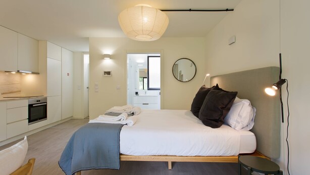 Un dormitorio moderno con cama, mesita de noche y vista a la cocina.
