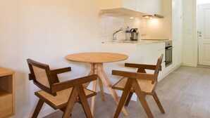 Una cocina moderna con armarios blancos, una mesa redonda para comer y dos sillas de madera.