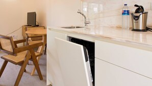 Una cocina moderna con armarios blancos, lavavajillas, un lavamanos, dispensador de agua y cafetera.
